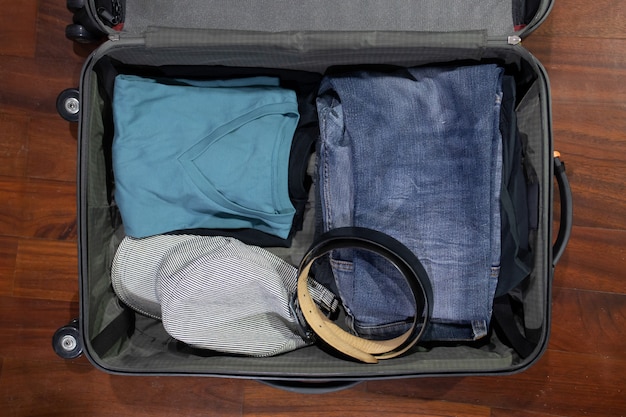 Flatlay of Open valise de voyage avec des vêtements sur le fond en bois