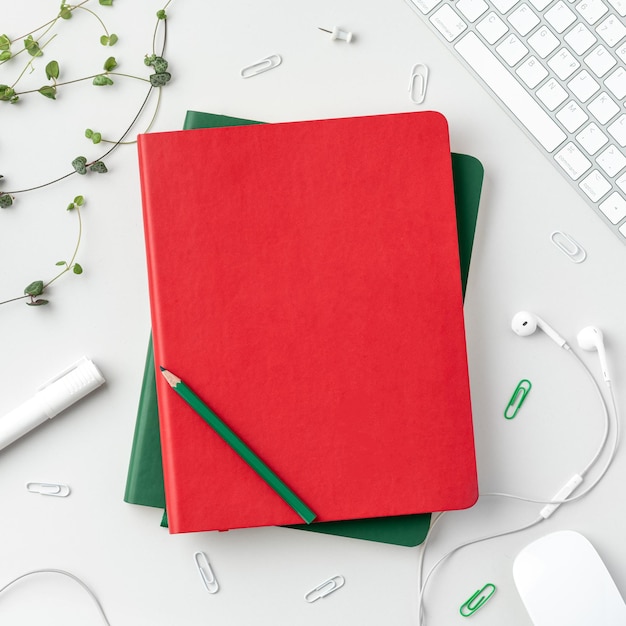 Photo flatlay de table de bureau à domicile vue de dessus de l'espace de travail avec des cahiers verts et rouges clavier souris marqueur crayon casque épingles et plantes sur fond blanc