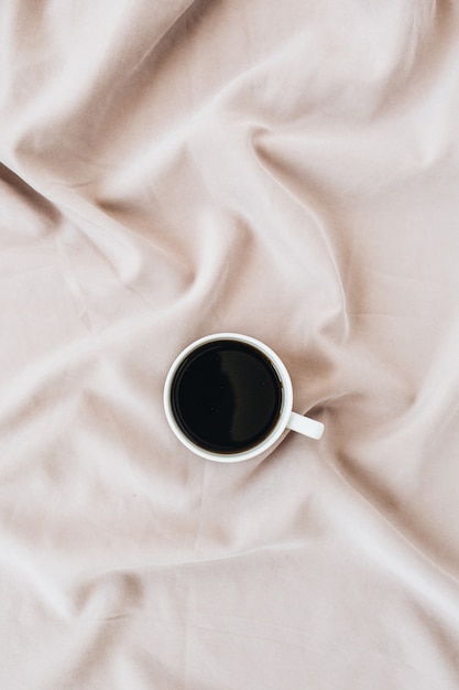 Flatlay de tasse de café noir sur une couverture rose pastel