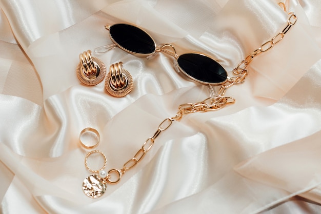 Flatley avec bijoux en or et perles sur fond de soie, lunettes dans le cadre