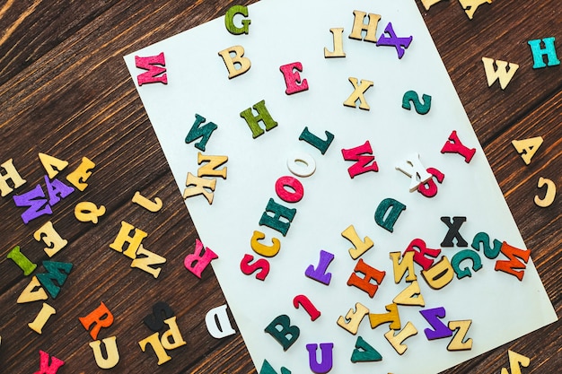 Flatley créatif de l'école. Sur une table en bois se trouvent des lettres multicolores avec l'inscription école.