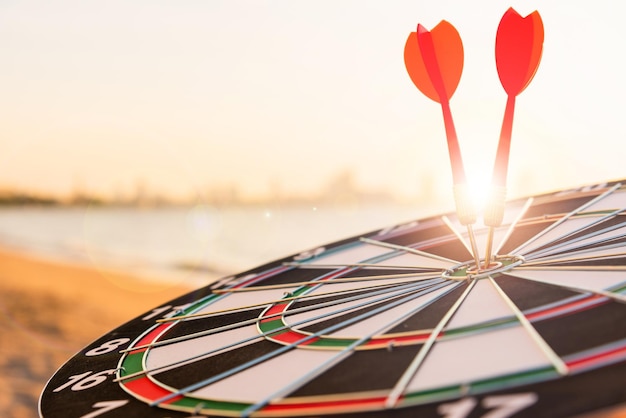 Photo la flèche de flèche frappant au centre sur le dartboard bullseye est la cible de l'entreprise de défi au coucher du soleil