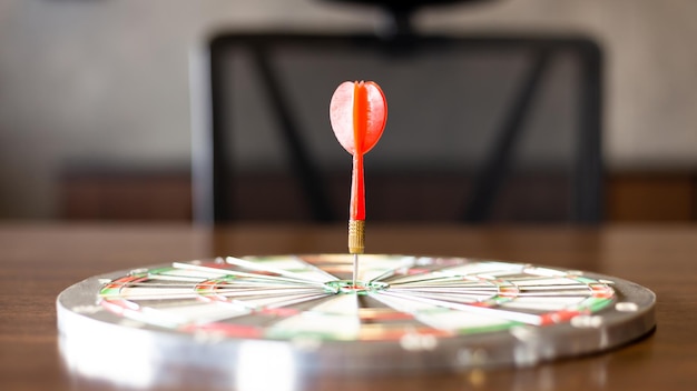 Une flèche de fléchette rouge vise le centre cible du jeu de fléchettes