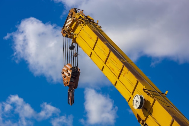 Flèche jaune d'une grue de chargement contre un ciel bleu avec des nuages