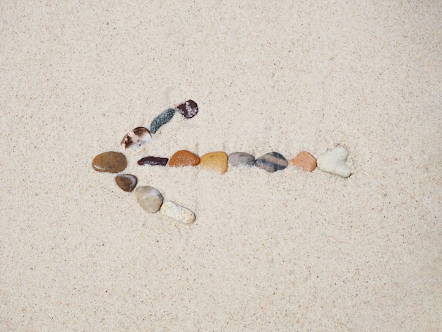 Flèche de pierres signe sur le sable de la plage.