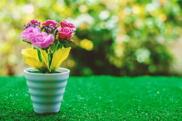 Fleur artificielle en pot de fleurs sur l&#39;herbe verte avec fond naturel flou