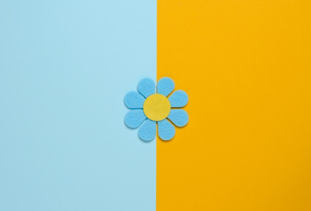 Fleur bleue en feutre sur fond bleu et orange.