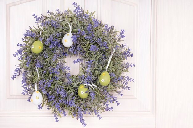 Fleur de bleuet tissée dans une couronne avec des oeufs peints accrochés à la porte la veille de Pâques