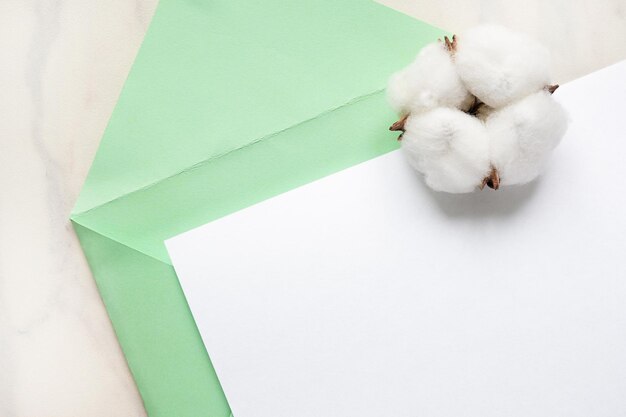 Fleur de coton et enveloppe verte et papier blanc