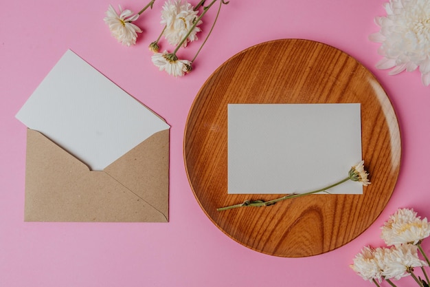 fleur d'enveloppe brune et carte blanche sur plaque de bois avec fond rose