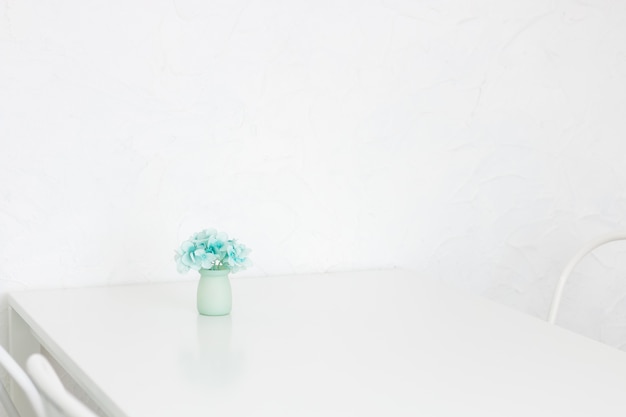 Photo fleur d'hortensia bleu dans un vase en céramique sur la table dans une belle salle blanche.