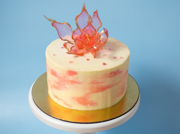 Une fleur d'isomalt rouge comestible sur un gâteau sur fond bleu