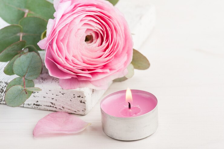 Fleur de renoncule rose avec bougie allumée