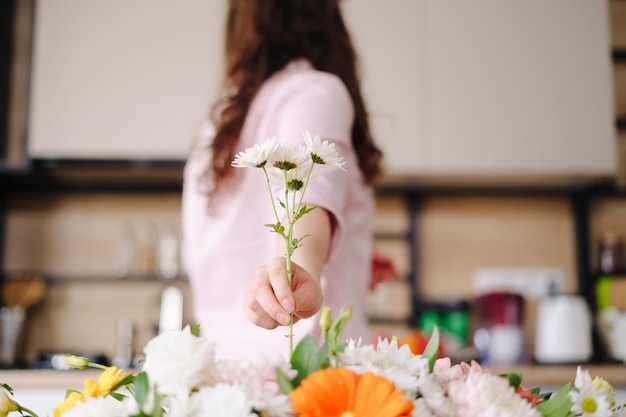 Fleuriste au travail vue arrière d'une main de femme brune organisant la dernière fleur dans sa composition moderne de mode à la maison
