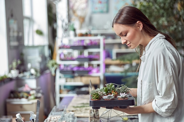 Fleuriste confiante travaille avec des fleurs séchées dans un magasin de fleurs confortable