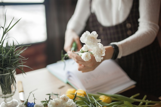 Fleuriste coupant des fleurs et réalisant une composition florale. Femme faisant un boquet avec des fleurs fraîches.