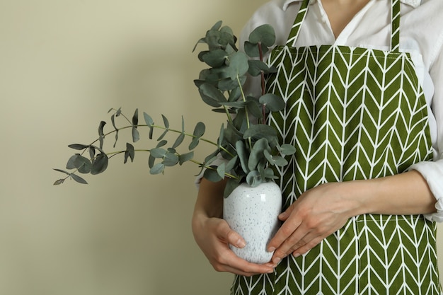 Fleuriste détient vase à l'eucalyptus sur fond beige clair