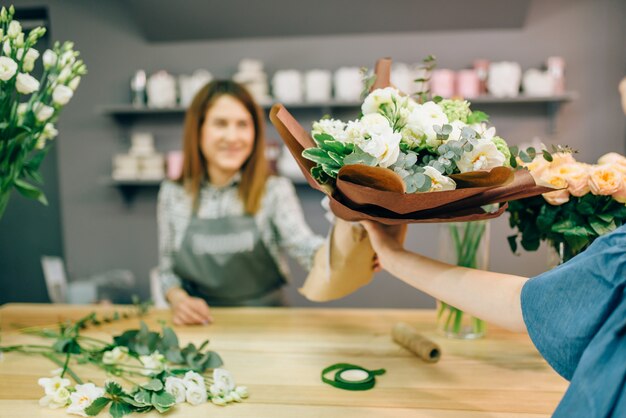 Le fleuriste donne un bouquet frais à une cliente