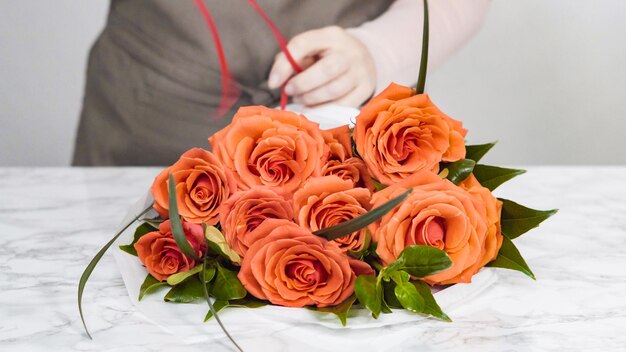 Fleuriste emballant des roses rouges dans un beau bouquet.