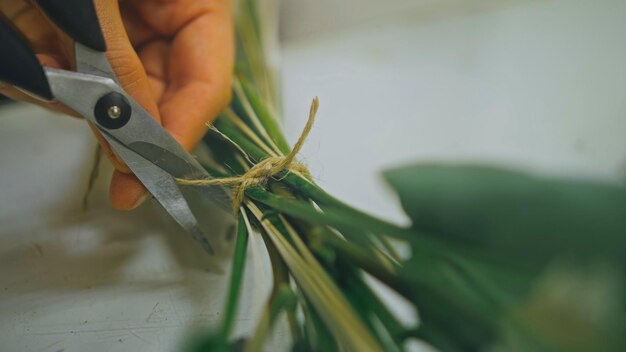 Une fleuriste fait un bouquet de fleurs qu'elle coupe du papier d'emballage w