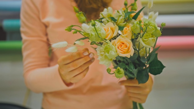 Une fleuriste fait un bouquet de fleurs qu'elle coupe du papier d'emballage w