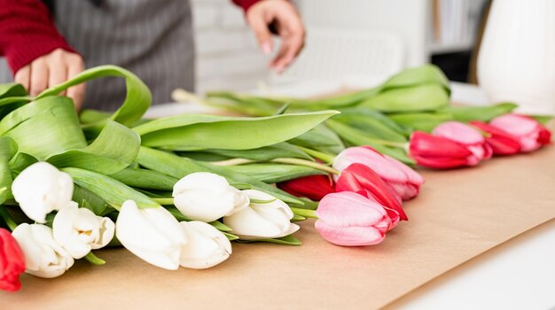 Une fleuriste fait un bouquet de tulipes fraîches et colorées.