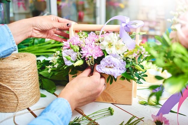 Le fleuriste fait la vue de dessus de bouquet sur le tableau blanc d'arrière-plan