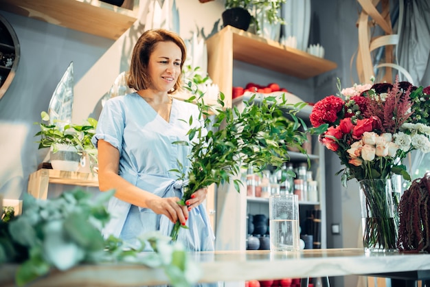 Fleuriste femelle détient des fleurs fraîches dans un magasin de fleurs. Entreprise de fleuristerie, fabrication de bouquet