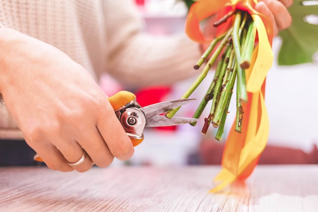 Fleuriste femelle élagage tige rose à table avec sécateur