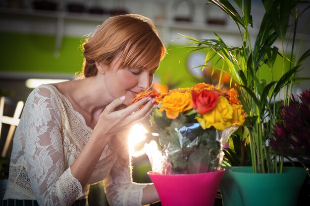 Fleuriste femelle sentant les fleurs roses