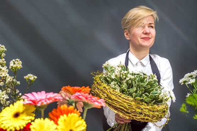 Fleuriste féminine au magasin de fleurs tenant un bouquet de fleurs avec un sourire.