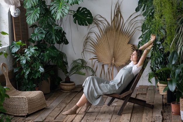 Fleuriste femme calme satisfaite se détendre dans le jardin intérieur profiter de l'équilibre mental et du bien-être à la maison