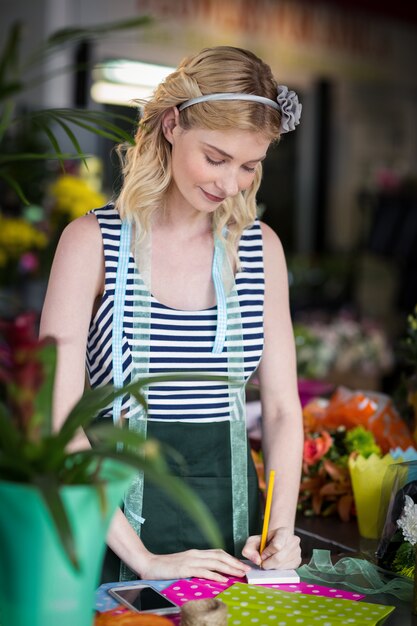 Fleuriste femme écrivant sur un bloc-notes