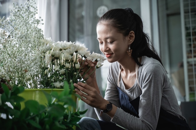 Fleuriste femme heureuse portant un tablier qui sent un beau bouquet