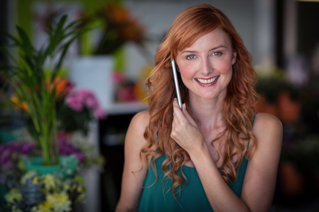 Fleuriste femme parlant sur téléphone mobile dans un magasin de fleurs