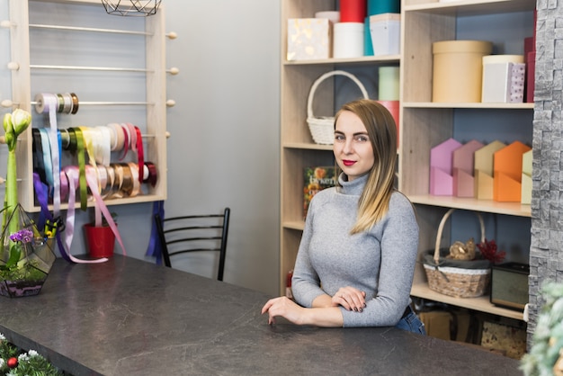 Fleuriste femme se tient à la réception dans un magasin de fleurs. Représentant des petites entreprises