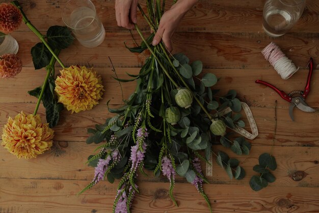 Fleuriste fille recueille un bouquet dans un atelier de fleurs sur un fond sombre mise en page pour la fleuristerie