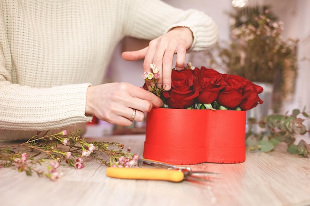 Fleuriste fleuriste femme faisant boîte avec roses rouges.