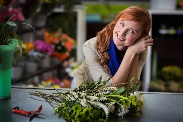 Fleuriste heureuse se penchant dans un magasin de fleurs