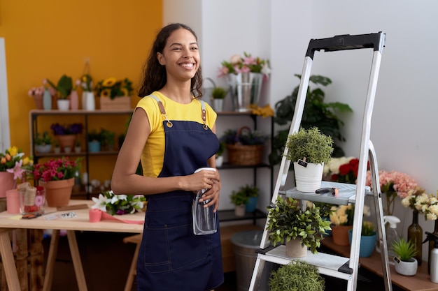 Fleuriste de jeune femme afro-américaine à l'aide d'une plante d'arrosage de diffuseur au magasin de fleurs