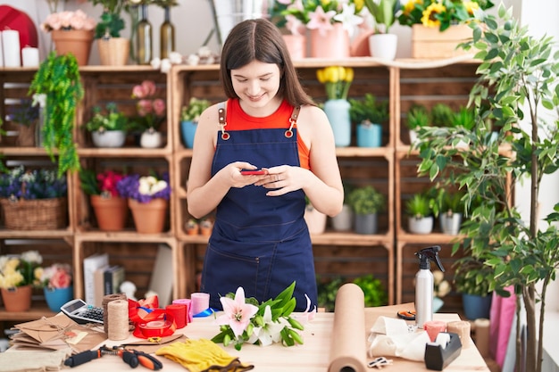 Fleuriste jeune femme caucasienne faire photo par smartphone aux fleurs chez fleuriste