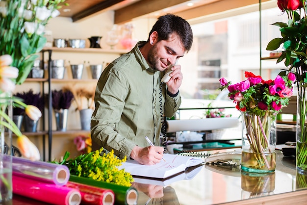 Fleuriste mâle accepte les commandes par téléphone dans un magasin de fleurs