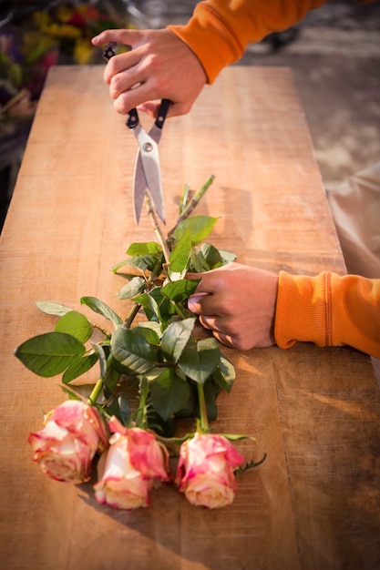 Fleuriste mâle coupe la tige de la fleur dans son magasin de fleurs