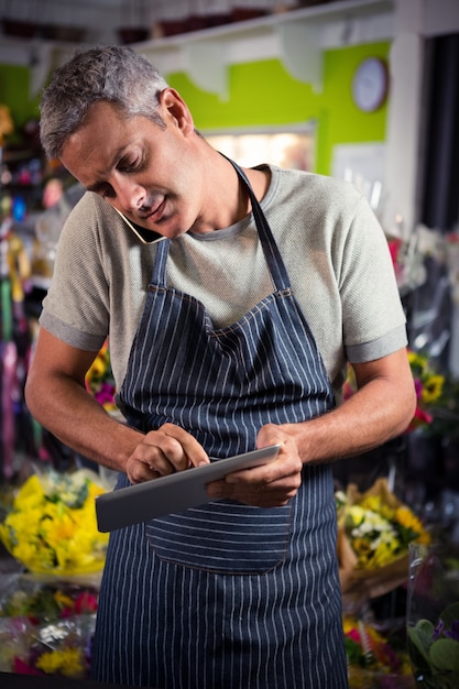 Fleuriste mâle prenant commande sur téléphone mobile