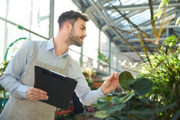 Fleuriste mâle prenant des notes sur le presse-papiers