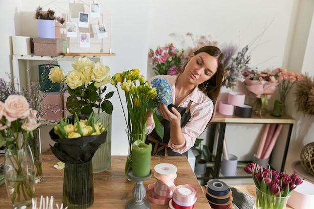 Fleuriste professionnel jeune femme fait des bouquets au magasin de fleurs