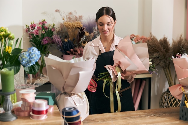 Fleuriste professionnel jeune femme fait des bouquets au magasin de fleurs