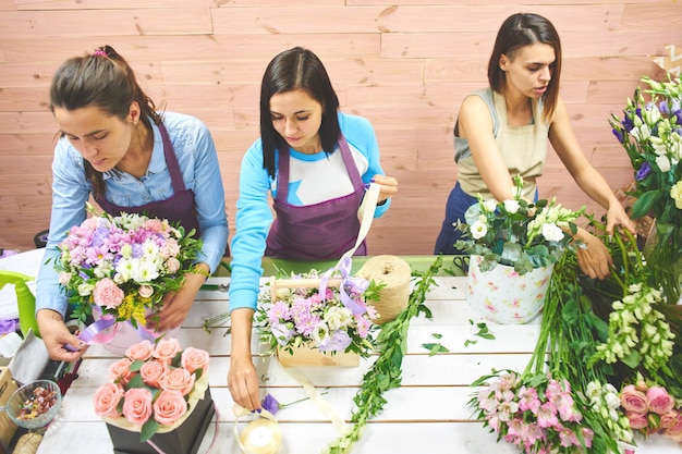 Fleuriste de trois filles travaillant avec des fleurs