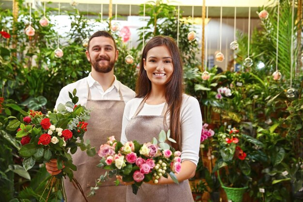 Fleuristes masculins et féminins avec de beaux bouquets en serre