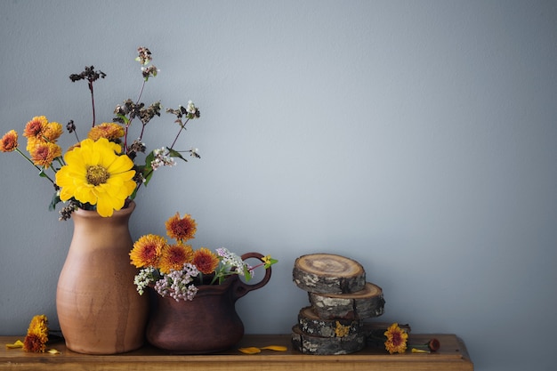 Fleurs d'automne dans un vase en céramique rustique sur fond gris mur